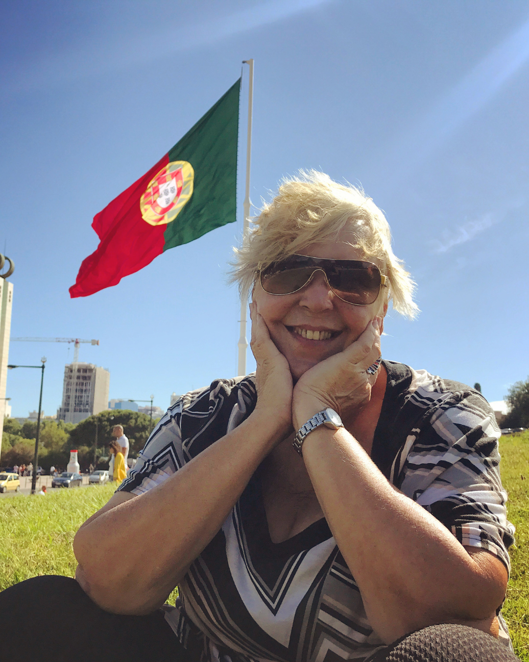 Marcia Kupstas sorrindo ao lado da bandeira de Portugal